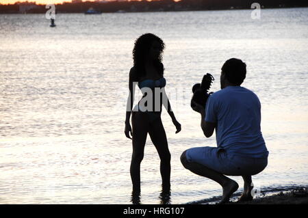 Fotograf nimmt Bilder eines Modells bei Sonnenuntergang auf dem Meer Miami Skyline bei Sonnenuntergang, von Key Biscayne Stockfoto