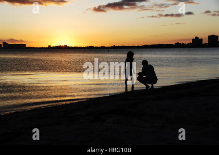 Fotograf nimmt Bilder eines Modells bei Sonnenuntergang auf dem Meer Miami Skyline bei Sonnenuntergang, von Key Biscayne Stockfoto