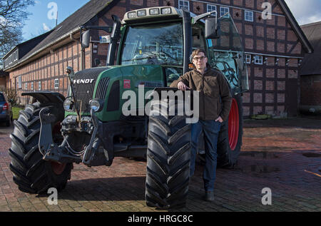 Wildeshausen, Deutschland. 24. Februar 2017. Bauer Niklas Behrens stand neben seinem Traktor durch einen Bauernhof in Wildeshausen, Deutschland, 24. Februar 2017. Der junge Mann hat den Hof übernommen. Foto: Carmen Jaspersen/Dpa/Alamy Live News Stockfoto