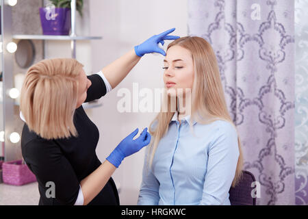 Seitenansicht der Kosmetikerin im schwarzen Kleid Reinigung Gesicht ihrer Kunden im Beauty-Salon Distanse durch Ergebnisse aus. Make-up Artist Gesicht CL berühren Stockfoto