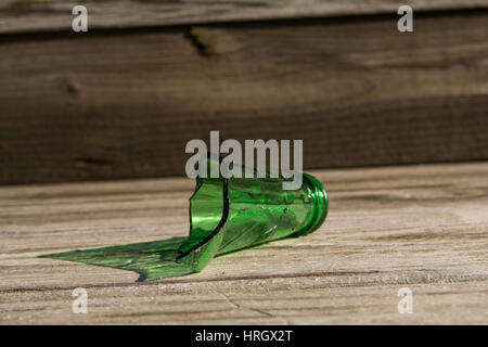 Gebrochene grüne Glasflasche mit Holz Hintergrund. Stockfoto