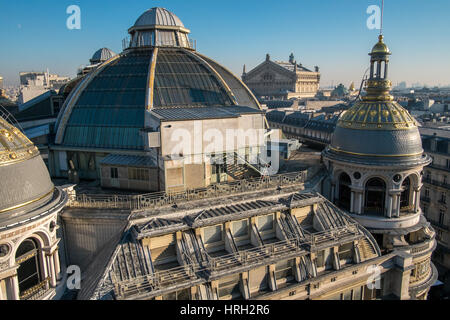 Die reich verzierten Kuppeln der das Kaufhaus Galeries Lafayette in der Wintersonne glänzen mit der Palais Garnier-Oper in der Ferne. Stockfoto