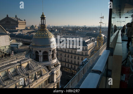 Die reich verzierten Kuppeln der das Kaufhaus Galeries Lafayette in der Wintersonne glänzen mit der Palais Garnier-Oper in der Ferne. Stockfoto