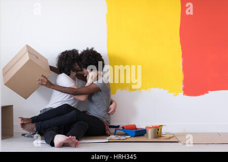 Glückliche junge multiethnischen paar entspannen und spielen mit Kartons nach einen Raum in ihrem neuen Haus auf dem Boden zu malen Stockfoto