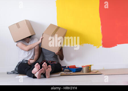 Glückliche junge multiethnischen paar entspannen und spielen mit Kartons nach einen Raum in ihrem neuen Haus auf dem Boden zu malen Stockfoto