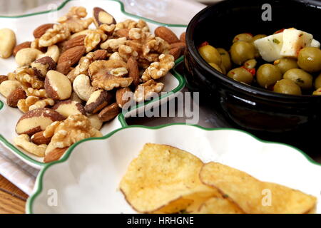 Oliven, Feta-Käse, Chips, Walnüsse, Mandeln, Cashewnüsse, Paranüsse und Haselnüssen mit einem Aperitif serviert Stockfoto