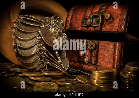 Schatztruhe, Stapel und Säule der Münzen und eine Keramikschale voller Schmuck Münzen in dunkler Umgebung Stockfoto