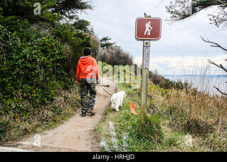 Ein Junge und sein Hund wandern auf einer Klippe in der Nähe von Meer mit Freifläche Stockfoto