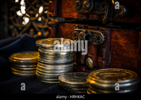 Schatztruhe, Säule der Münzen und Kerze Lampe in dunkler Umgebung Stockfoto