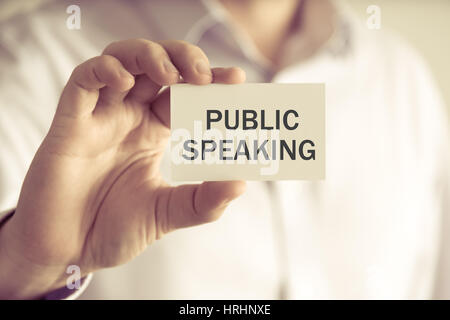 Closeup auf Geschäftsmann hielt eine Karte mit Text PUBLIC SPEAKING, Firmen-Konzept-Image mit soft-Fokus-Hintergrund und Vintage-Ton Stockfoto