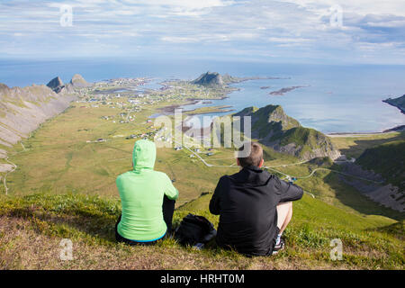 Paar auf Gipfel bewundern Meer umrahmen das Dorf Sorland, Vaeroy Insel, Nordland Grafschaft, Lofoten Inseln, Norwegen Stockfoto