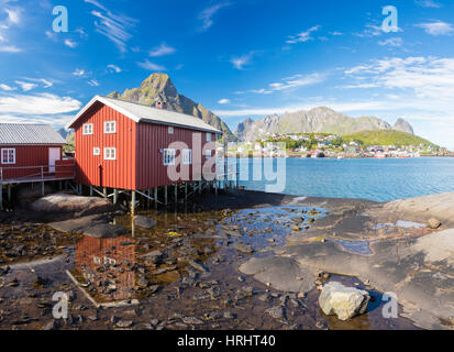 Typisches Haus der Fischer namens Rorbu spiegelt sich im blauen Meer, Reine, Moskenesoya, Lofoten Inseln, Norwegen, Skandinavien Stockfoto