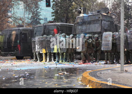 Eine Linie der chilenischen Polizei Demonstranten beobachten, die Flaschen mit Farbe, während einer Demonstration in der Innenstadt Santiagos, Chile warf Stockfoto