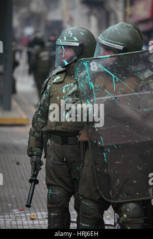 Eine Linie der chilenischen Polizei Demonstranten beobachten, die Flaschen mit Farbe, während einer Demonstration in der Innenstadt Santiagos, Chile warf Stockfoto