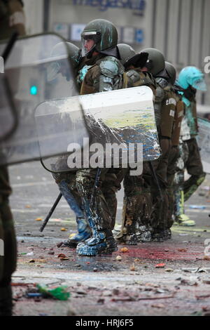 Eine Linie der chilenischen Polizei Demonstranten beobachten, die Flaschen mit Farbe, während einer Demonstration in der Innenstadt Santiagos, Chile warf Stockfoto