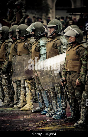 Eine Linie der chilenischen Polizei Demonstranten zu beobachten, die Flaschen mit Farbe, während einer Demonstration in der Innenstadt von Santiago, Chile warf. Stockfoto