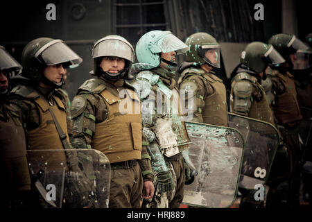 Eine Linie der chilenischen Polizei Demonstranten zu beobachten, die Flaschen mit Farbe, während einer Demonstration in der Innenstadt von Santiago, Chile warf. Stockfoto