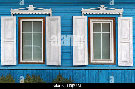 Zwei Fenster mit einer offenen Sonnenblenden im alten zerstörten blau Retro-Holzhaus. Panorama Collage aus mehreren Fotos Stockfoto