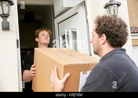 Umzüge-Geschäft. Zwei Männer heben und tragen eine verpackte Schachtel aus einem Haus. Stockfoto