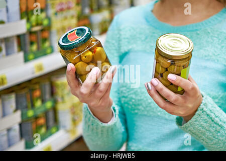 Frau wählt aus der Dose Oliven im Supermarkt Stockfoto