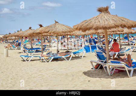 Touristen entspannen unter reetgedeckten Tiki Sonnenschirme im Riu Karamboa Resort, Boa Vista, Kap Verde (Cabo Verde), Afrika Stockfoto