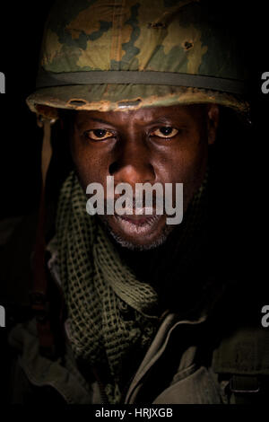 Porträt des afroamerikanischen Soldaten aus der Zeit des Vietnam-Krieges vor einem schwarzen Hintergrund. Dunkle Schatten für ein dramatischer Bild verwendet. Stockfoto