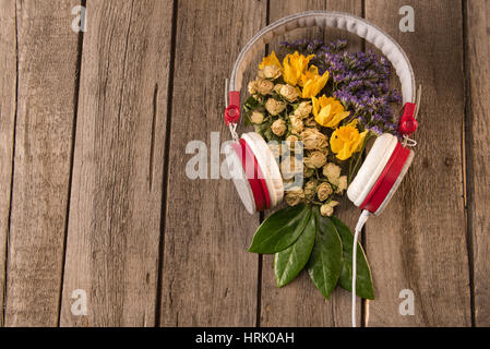 Draufsicht der Frühling florale Komposition mit Kopfhörer und die Vielfalt der Blüten und Blätter auf Holztisch Stockfoto