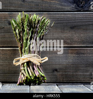 Nahaufnahme der leckere Natur- und vitaminreiche frische Spargel frisch gepflückt auf dem Lande, fotografiert auf einem alten Holztisch. Stockfoto