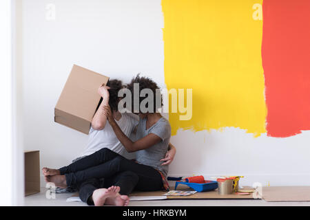 Glückliche junge multiethnischen paar entspannen und spielen mit Kartons nach einen Raum in ihrem neuen Haus auf dem Boden zu malen Stockfoto