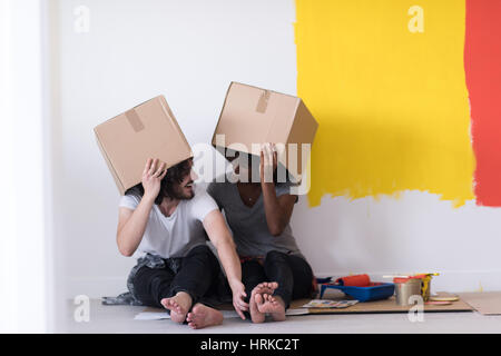 Glückliche junge multiethnischen paar entspannen und spielen mit Kartons nach einen Raum in ihrem neuen Haus auf dem Boden zu malen Stockfoto