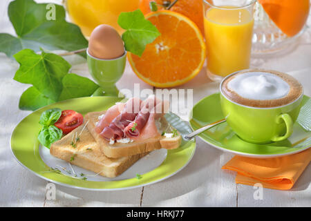 Frühstück mit Schinken-Toast, ein gekochtes Ei, Orangensaft und eine Tasse cappuccino Stockfoto