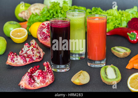 drei Gläser von verschiedenen frischen Saft. Rüben, Karotten und Kiwi Säfte auf grauem Hintergrund. Stockfoto