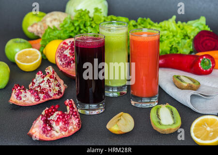 drei Gläser von verschiedenen frischen Saft. Rüben, Karotten und Kiwi Säfte auf grauem Hintergrund. Stockfoto