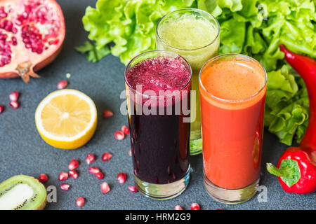 drei Gläser von verschiedenen frischen Saft. Rüben, Karotten und Kiwi Säfte auf grauem Hintergrund. Stockfoto