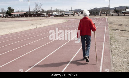 Ältere Frau zu Fuß auf einem Leichtathletik-Stadion Stockfoto