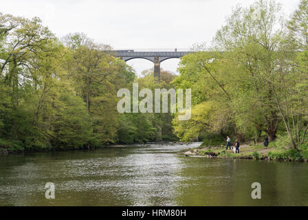 Ein Mann Frau und Hund durch den Fluss Dee bei Wanderern und ein Kanal Schiff überquert das Pontcysyllte-Aquädukt im Hintergrund Stockfoto