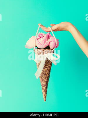 Blumenstrauß in weiblicher Hand auf eine türkisfarbene Wand Hintergrund Pfingstrosen. Textfreiraum Stockfoto
