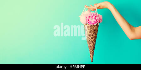 Blumenstrauß in weiblicher Hand auf eine türkisfarbene Wand Hintergrund Pfingstrosen. Textfreiraum Stockfoto