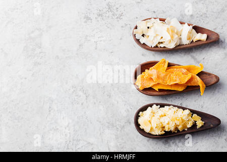 Gesunde Snacks. Getrocknete Mango, Kokos-Chips und Palmzucker in Holzschalen. Grauen Stein Hintergrund. Textfreiraum Stockfoto
