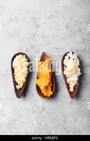 Gesunde Snacks. Getrocknete Mango, Kokos-Chips und Palmzucker in Holzschalen. Grauen Stein Hintergrund. Textfreiraum Stockfoto