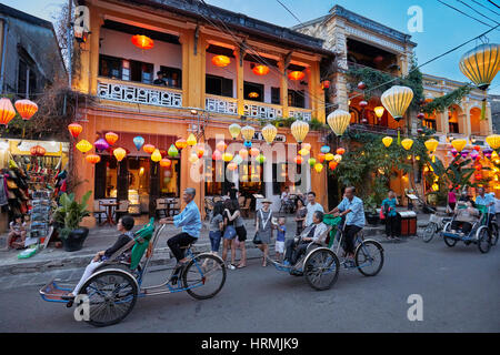 Touristen auf eine Fahrt mit der Fahrradrikscha in Hoi An Altstadt leuchtet in der Dämmerung. Hoi An, Provinz Quang Nam, Vietnam. Stockfoto