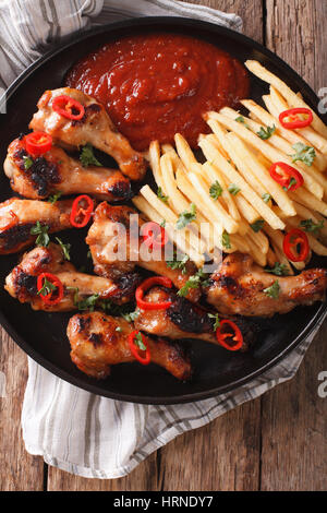 Gegrillte Hähnchenflügel mit Pommes und Ketchup auf den Tisch-Nahaufnahme. vertikale Ansicht von oben Stockfoto