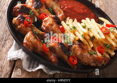 Würziger BBQ-Hähnchenflügel mit Pommes Frites und Soße auf einer Platte Nahaufnahme. horizontale Stockfoto