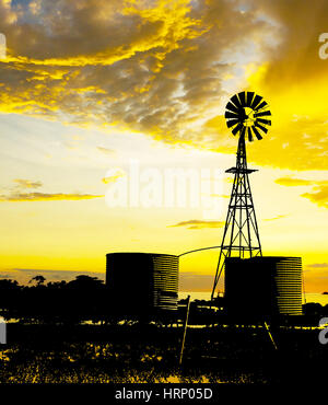 Silhouette der Windmühle und Wassertanks im australischen Outback gegen dramatischen Wolkenformationen.  Die Grafik der Kombination von zwei Bildern.  Cloud-Aufnahme Stockfoto