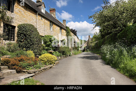 Einer Reihe der terrassenförmig angelegt Cottages in einer traditionellen Cotswold Dorfstraße Stockfoto