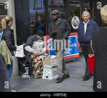 Obdachloser bittet in einem Wheelhair, die Welt vorbei entlang der 42nd Street in Times Square in New York City. Stockfoto