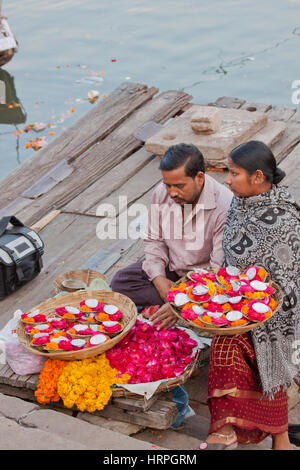 Indische Händler in Varanasi an den Ufern des Ganges, Verkauf, Blütenblätter, kleine Girlanden und Öl Miniaturlampen für Hindu Andachten Stockfoto