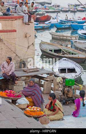 Indische Händler in Varanasi an den Ufern des Ganges, Verkauf, Blütenblätter, kleine Girlanden und Öl Miniaturlampen für Hindu Andachten Stockfoto