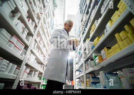 Niedrigen Winkel Ansicht der senior männlichen Chemiker stehen Regale in Apotheke Stockfoto