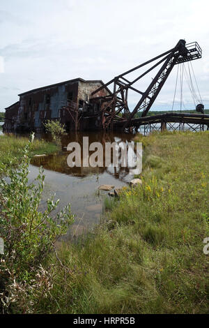 Eine alte, verlassene Bagger für den Bergbau ist teilweise im Wasser untergetaucht. Stockfoto